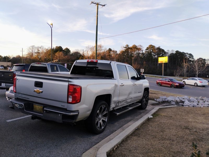 A clean silver Chevrolet Silverado on new wheels at golden hour