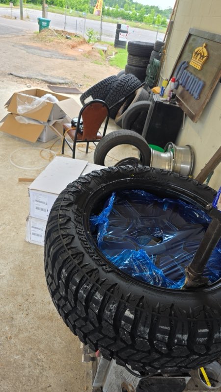 A new chunky off-road mud tire mounted on a blue wheel at the shop